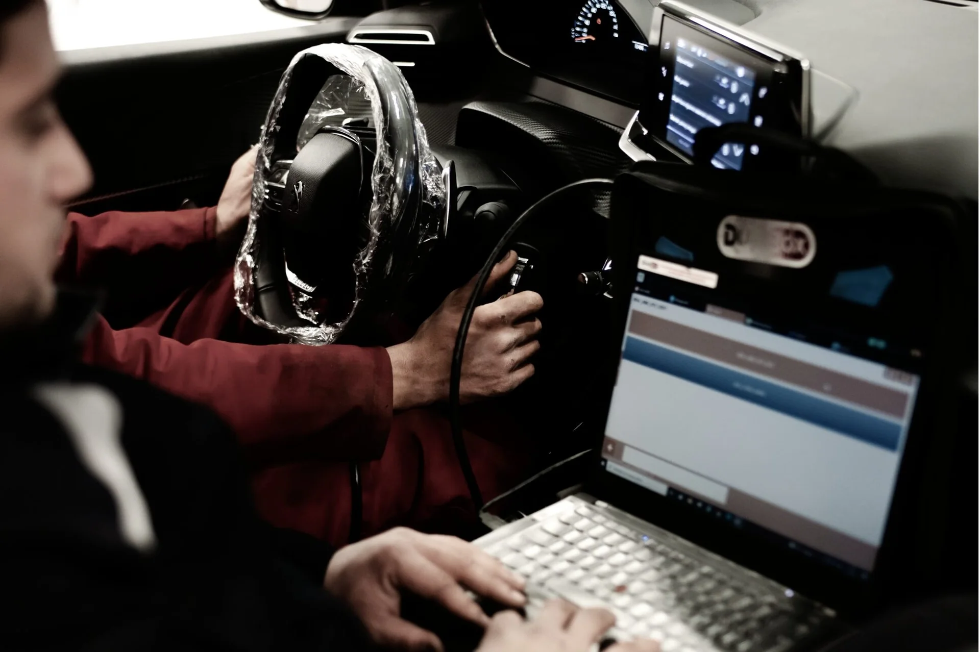 Technician using a diagnostic laptop beside a vehicle