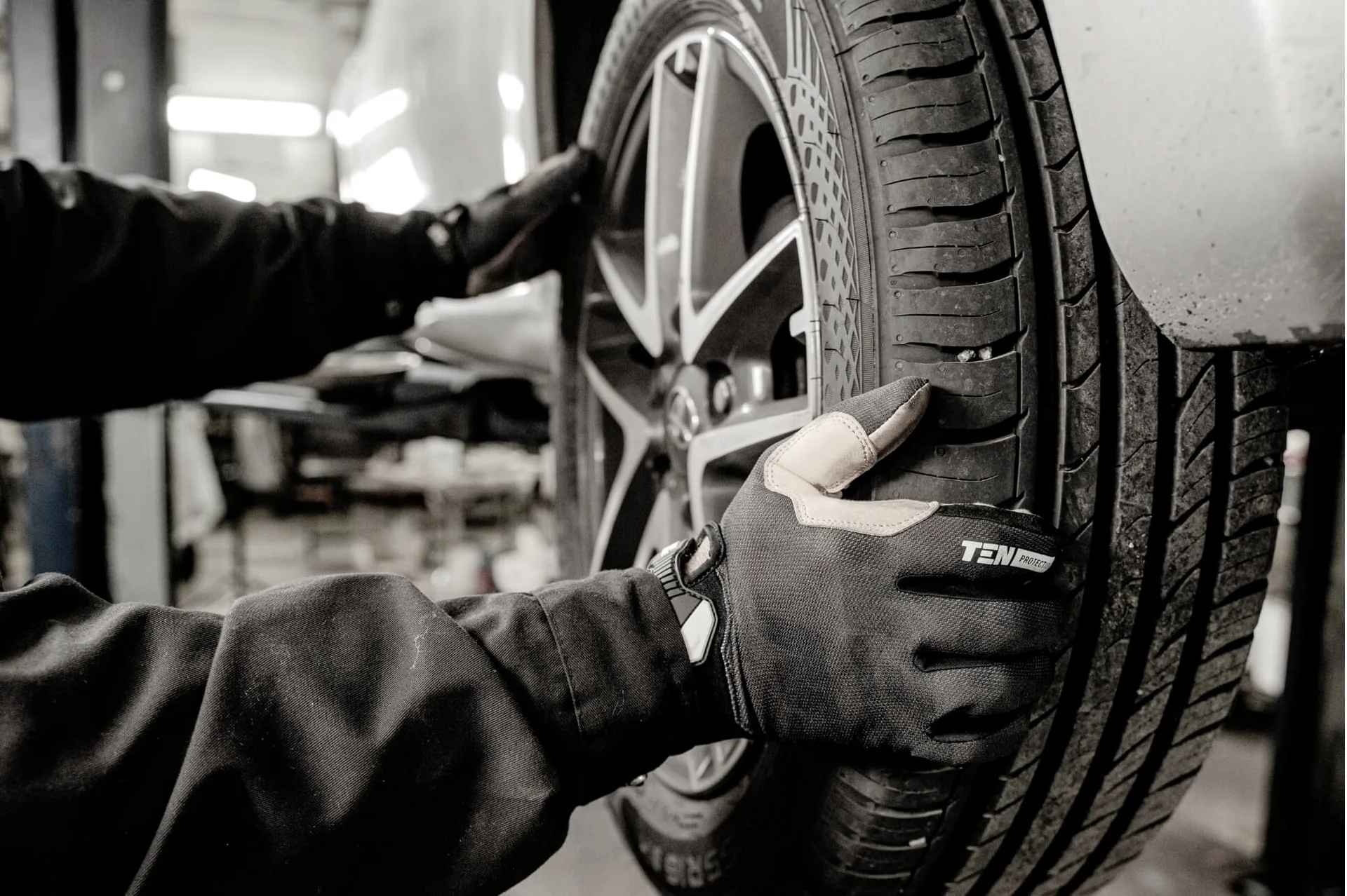 Gloved hands carefully positioning a tire on a vehicle