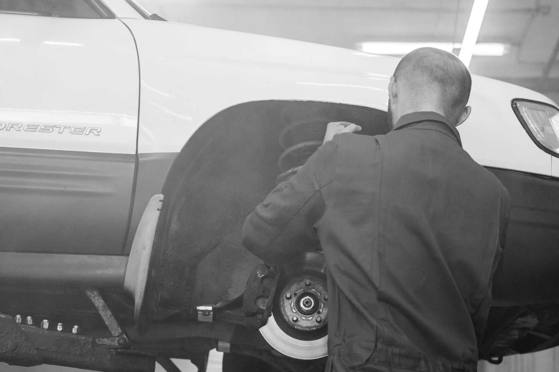 Technician working near a raised vehicle wheel